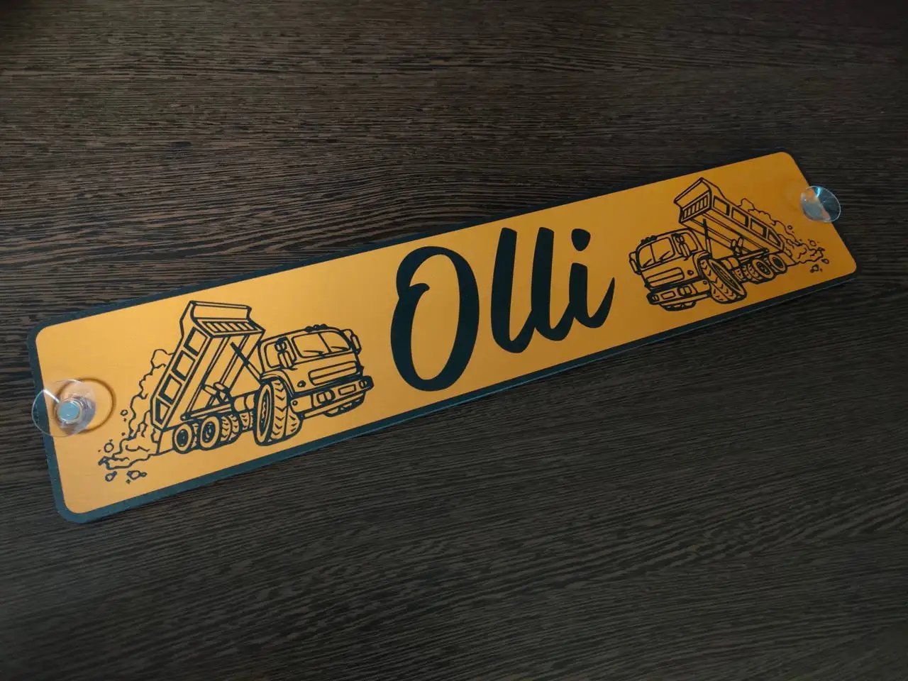 Personalized LKW nameplate with truck image, featuring the name 'Olli' on a wooden surface.