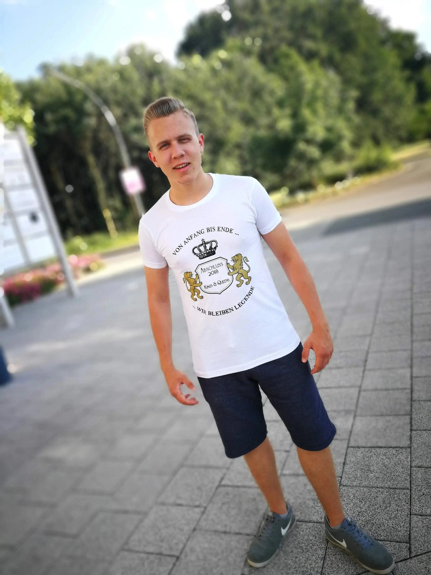 Young man wearing stylish custom graduation t-shirt with unique print, standing outdoors in casual attire.