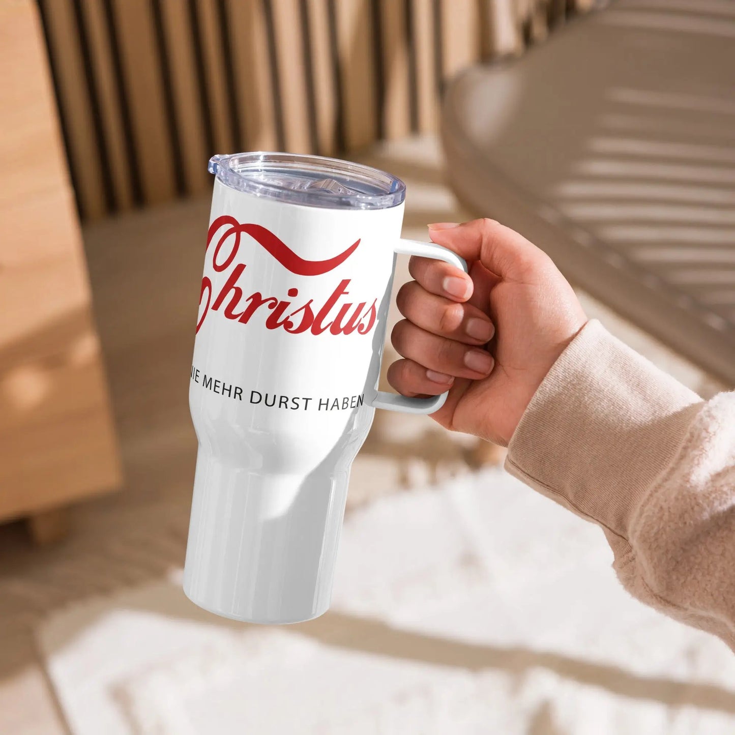 Person holding a travel mug with 'ERLEBE Jesus Christus' printed, featuring an ergonomic handle and leak-proof lid for convenience.