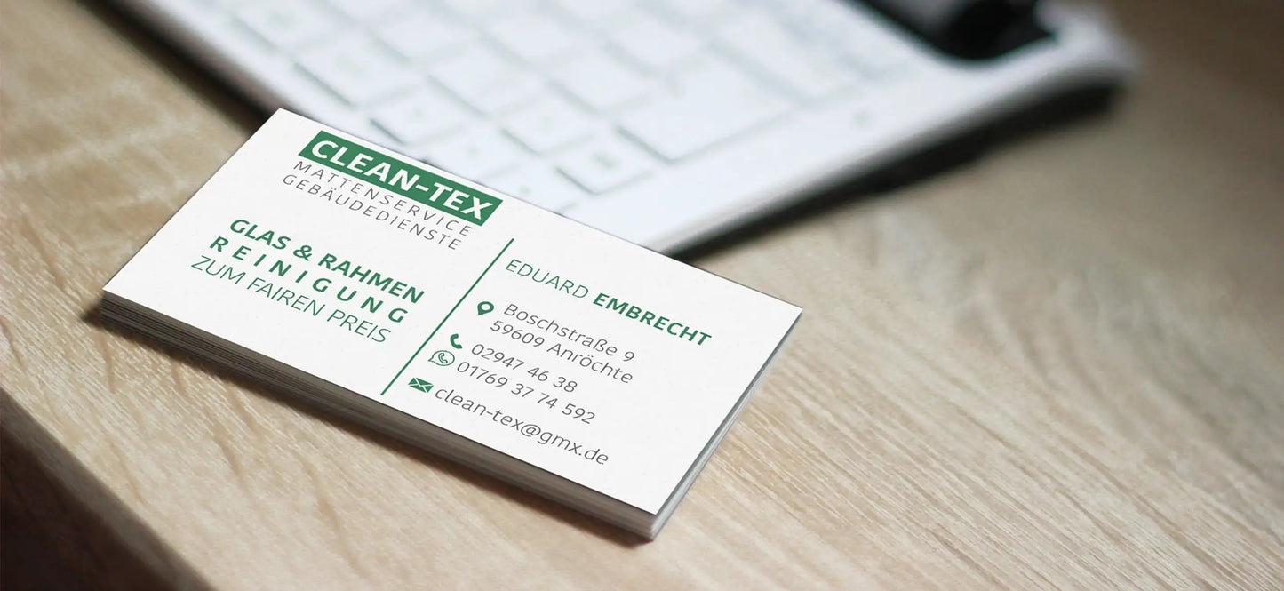 Business card on a wooden desk with contact information and Clean-Tex logo, next to a keyboard.