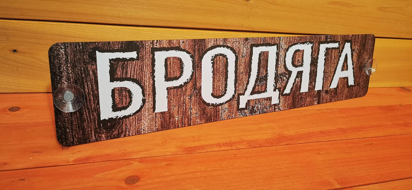 Truck nameplate with rustic wood design and Cyrillic text, mounted on a wooden surface using suction cups.