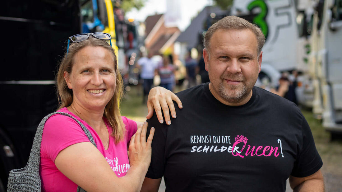 Two attendees at TruckTreff Kaunitz 2022 smiling, showcasing custom truck shirts.