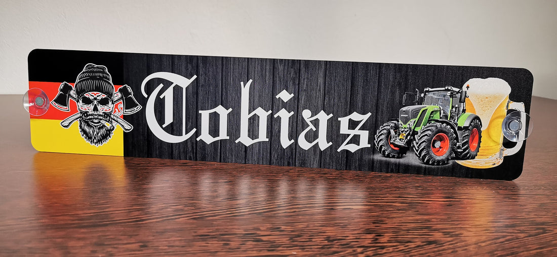 LKW Namensschild mit Namen Tobias, Totenkopf-Design, Traktor und Bier, auf holzähnlichem Hintergrund.