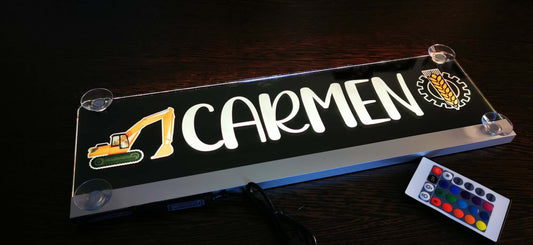 Beleuchtetes LKW Namensschild mit Aufschrift "Carmen" und Fernbedienung auf dunklem Hintergrund