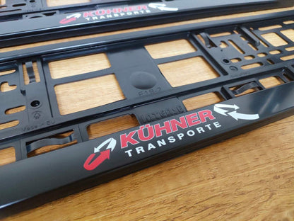 Schwarze Kennzeichenhalter mit individuellem Aufdruck "Kühner Transporte", 2 Stück, UV-beständig und frostfest.