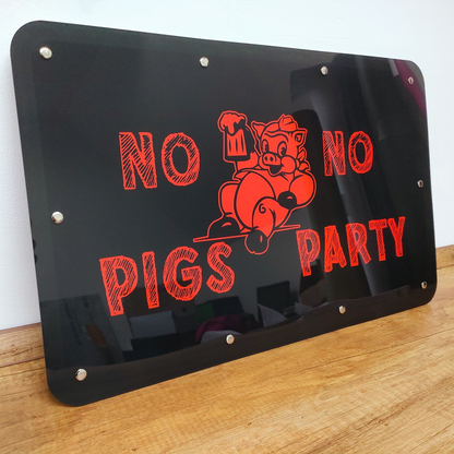 "No Pigs No Party" sign with red letters and pig graphic on a black background, mounted on a wooden surface.