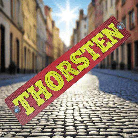 THORSTEN nameplate with suction cups displayed on a cobblestone street, showcasing vibrant yellow text on a red background.