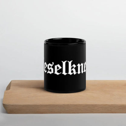 Schwarze glänzende Keramiktasse mit "Dieselknecht" Aufdruck, auf Holzunterlage stehend, ideal für Kaffee oder Tee.