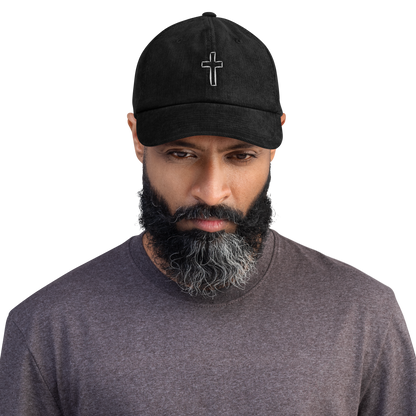 Man wearing a black cord cap with cross embroidery, showcasing style and durability.