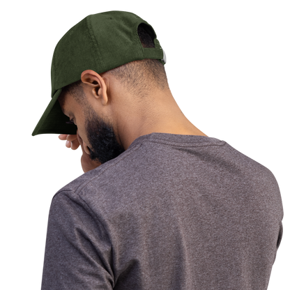 Person wearing green cord cap with stylish cross embroidery, showcasing durable and comfortable design.