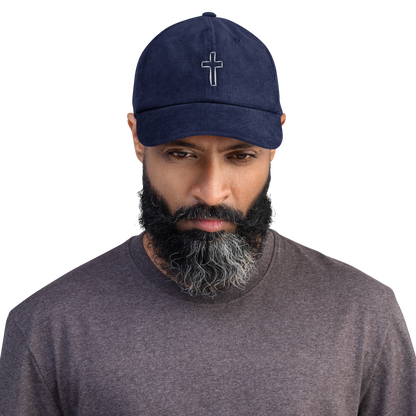 Man wearing blue cord cap with cross embroidery showcasing stylish and durable headwear.