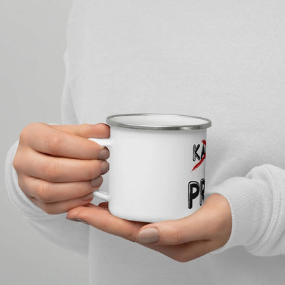 Person holding a white enamel PRIPS Tos mug, ideal for coffee or tea, featuring bold black lettering and a sturdy handle.