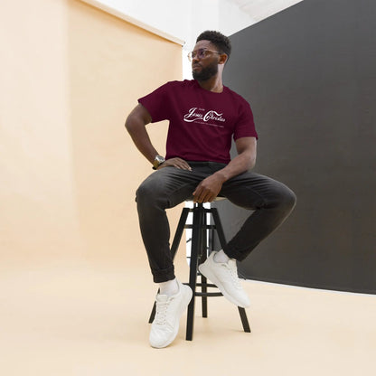 Man wearing 'Erlebe Jesus Christus und du wirst nie mehr Durst haben' T-shirt, sitting on a stool in a studio setting.