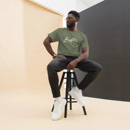 Man wearing a green T-shirt with 'Erlebe Jesus Christus' print, seated on a stool in a stylish studio setting.