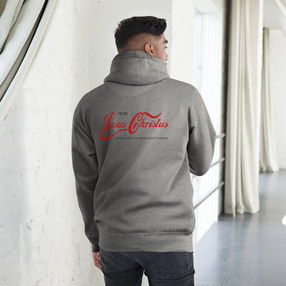 Man wearing grey hoodie with red text 'Erlebe Jesus Christus und du wirst nie mehr Durst haben' in stylish indoor setting.