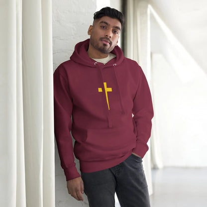 Man wearing maroon hoodie with yellow cross design, standing indoors.
