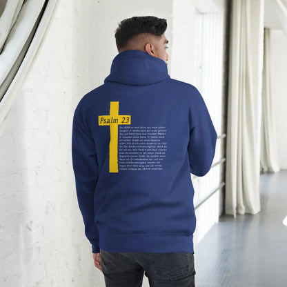 Man wearing blue hoodie with Psalm 23 and cross design on back, standing indoors for stylish and meaningful fashion statement.