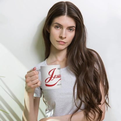 Woman holding a printed mug with 'Erlebe Jesus Christus und du wirst nie mehr Durst haben' in red lettering.
