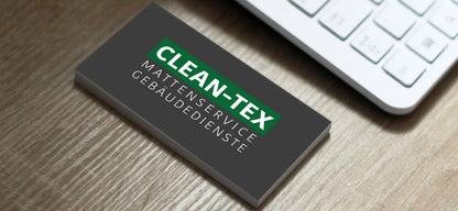 Business card for CLEAN-TEX Mattenservice Gebäudedienste on wooden surface next to keyboard.