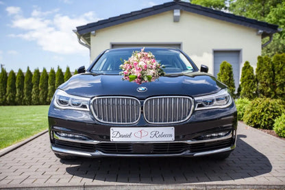Wedding car with custom license plate and floral decoration, parked outdoors in front of a house, designed for a special occasion.