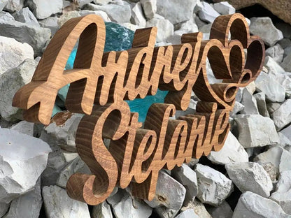 3D wooden family name sign 'Andrej Stefanie' on rocks, handcrafted from solid wood for indoor and outdoor use.