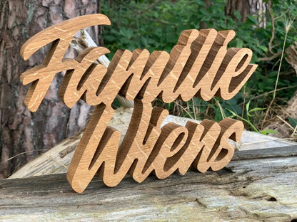 3D Familienname aus Echtholz mit geschwungener Schrift, geeignet für den Außenbereich. Schriftzug "Familie Wiens" auf Holzuntergrund.