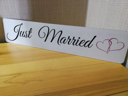 Elegant "Just Married" wedding car sign with heart design on wooden table.