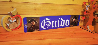 Personalisierte LKW Namensschild mit "Guido" Motiv, auf Alu-Verbundplatte gedruckt, im rustikalen Raum mit Dekorationen.