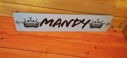 Personalized truck nameplate with 'Mandy' in bold script between crown motifs, mounted on a wooden background.