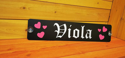 Custom truck nameplate with "Viola" and pink hearts, mounted on wood background with suction cups.