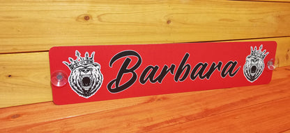 Red LKW nameplate with 'Barbara' in black script, featuring lion graphics, mounted on wood paneling.