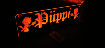 Illuminated LED truck name tag with 'Püppi' design, featuring suction cups, ideal for enhancing LKW cabins with customizable motifs.