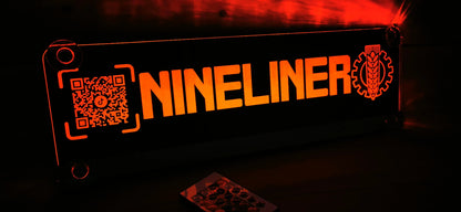 Illuminated LED truck nameplate with custom motif, featuring QR code and 'NINELINER' text, for truck driver's living space.