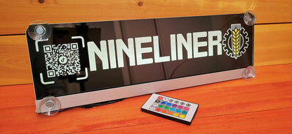 LED illuminated LKW nameplate with suction cups displaying 'NINELINER' and control remote on a wooden surface.