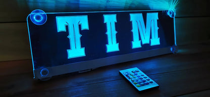 Illuminated LED truck nameplate with "TIM" and remote, featuring suction cup attachment for personalized decor.