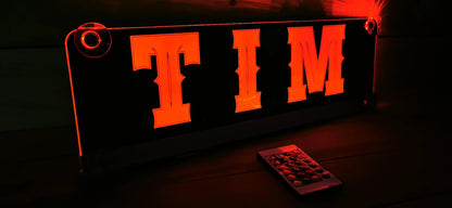 Illuminated LED truck nameplate with suction cups and customizable design, featuring bright orange 'TIM' letters.