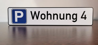 Parkplatzschild mit der Aufschrift 'Wohnung 4' auf einem Tisch, gedruckt auf wetterfestem Aludibond.