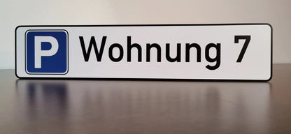 Schild mit blauem Parkplatzsymbol und Beschriftung "Wohnung 7" auf Aludibond für individuelle Parkplatzkennzeichnung