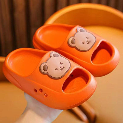 Bright orange kids' slippers with cute bear design, offering comfort and style for children's feet.