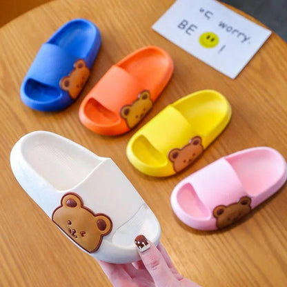 Colorful Wolkenflitzer children’s slippers with teddy bear design on a wooden table, showcasing comfort and style for little feet.